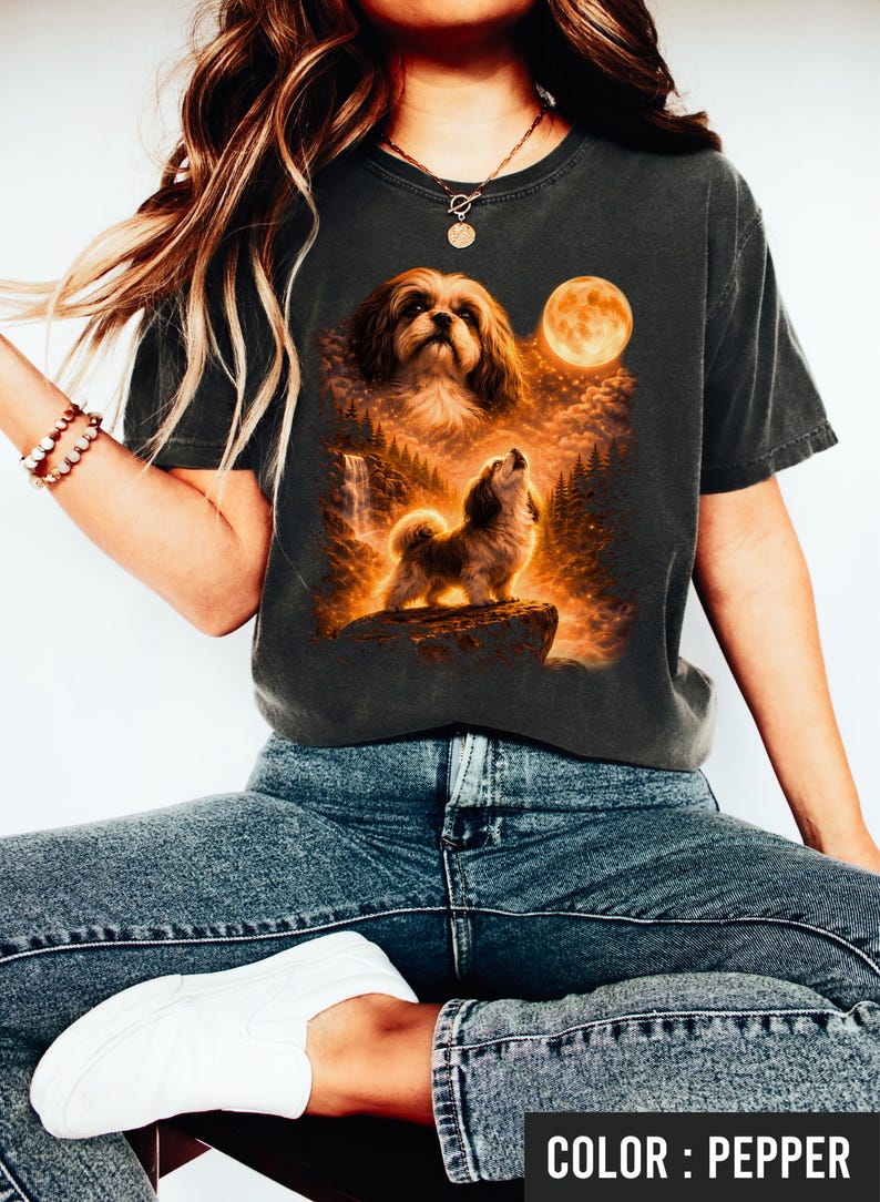 Puede incluir: Camiseta gris oscuro con un gr&aacute;fico detallado de un perro aullando a la luna, con una cascada y un bosque. La camiseta es de color pimienta. La imagen incluye el texto "COLOR : PEPPER".