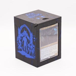 May include: Black card storage box with blue detailing. The box has a blue illustration of figures and a castle. The top of the box has the text "Rise of the Rolling". A card with the text "Wilhelt, the Rotcleaver" is visible.