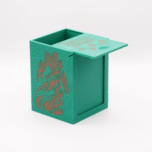 May include: A teal-colored card storage box with a flip-top lid. The box features a detailed embossed design and a copper-colored illustration of a figure. The lid has the text "Dark of Elements" printed on it.