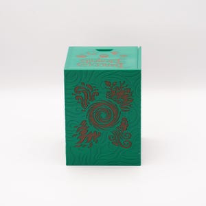 May include: A green box with embossed floral designs and the words "Dungeons & Dragons Elements" in orange. The box is square and has a slot on the top. The floral design is a reddish-brown color.