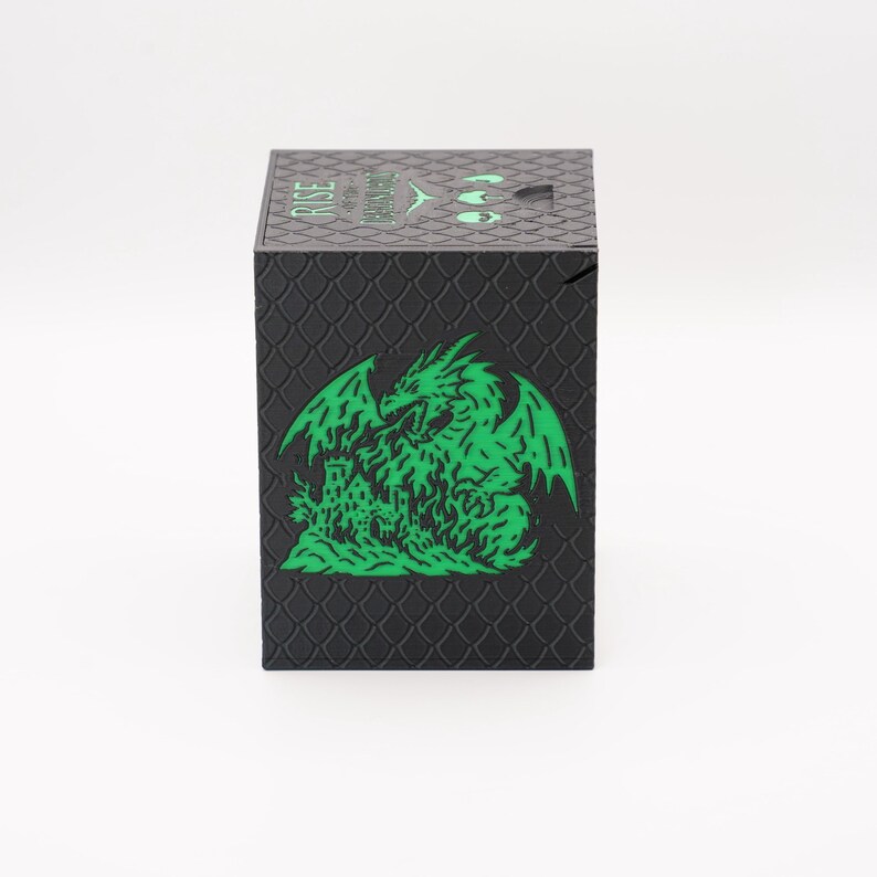 May include: Black box with a textured, scale-like pattern. A green dragon and castle graphic is on the front. The top of the box has the word "RISE" and other text in green. The box is square and appears to be a product package.