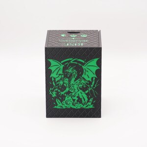 May include: Black box with a green dragon graphic. The box has a textured surface and the words "RISE DRAGONFORDS" are printed on the top. The dragon is depicted with wings and a detailed body.