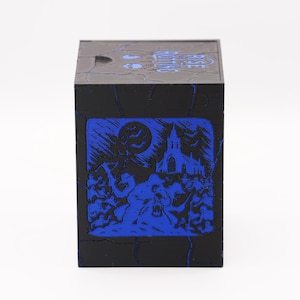 May include: Black cube-shaped box with a blue illustration of a spooky scene. The design features a full moon, bats, a church, and figures. The top of the box has the text "Grave Robbing".
