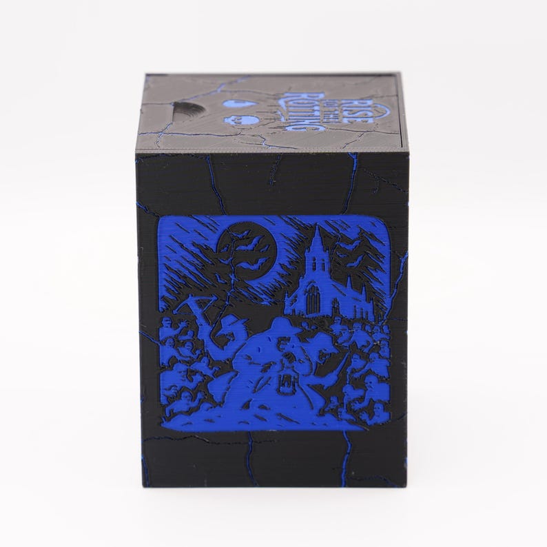 May include: Black cube-shaped box with a blue illustration of a spooky scene. The design features a full moon, bats, a church, and figures. The top of the box has the text "Grave Robbing".