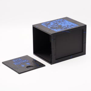 May include: Black box with a removable lid, featuring blue artwork and the text "RISE OF THE ROTTING". The box has a square shape and is open, revealing the interior. The lid is separate and also has blue artwork.
