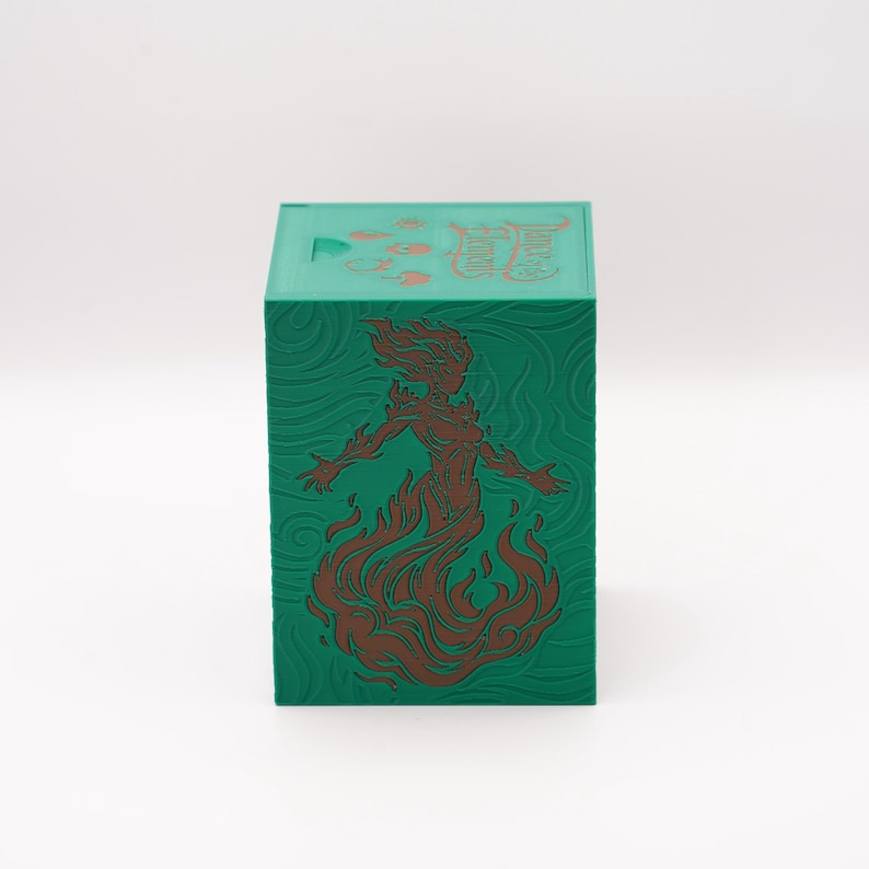 May include: A green box with a detailed design. The box features a brown illustration of a woman engulfed in flames. The top of the box has Chinese characters and other symbols. The box is a cube shape.