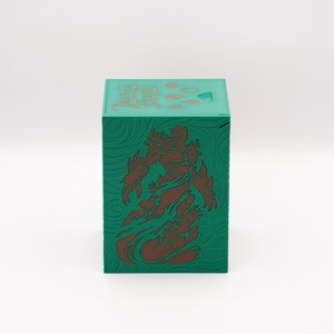 May include: A green box with a brown illustration of a figure on the front. The box has a textured surface with a swirling pattern. The top of the box has Chinese characters.