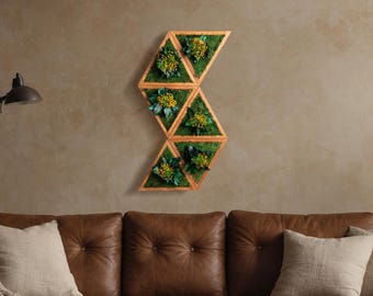 May include: A wooden wall planter with a geometric design. The planter is made up of five triangular sections, each with a small plant growing inside. The planter is mounted on a wall, and the plants are all green.