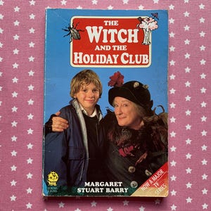 May include: A vintage book cover for "The Witch and the Holiday Club" features a blue background with the title in red and white. The cover shows a boy and an older woman. The author's name, Margaret Stuart Barry, is also visible.