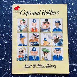 Puede incluir: Un libro infantil vintage titulado "Cops and Robbers" de Janet & Allan Ahlberg. La portada presenta ilustraciones de dibujos animados de varios personajes, incluidos policías y criminales, en un diseño de cuadrícula. El logotipo de Little Mammoth es visible.