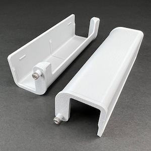 May include: Two white plastic pieces that fit together to create a wall-mounted paper towel holder. The pieces are shown separated, with one piece having a screw visible.