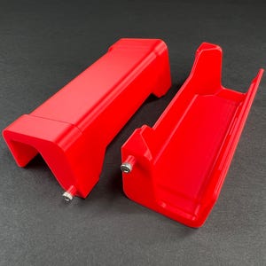 May include: Two bright red plastic parts that fit together to form a case or container. The parts are made of a smooth, glossy plastic.