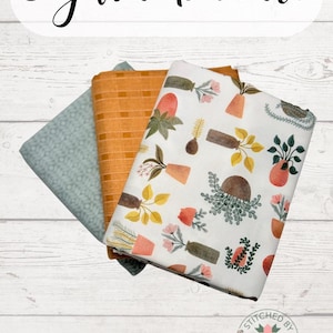 May include: A fabric bundle featuring three different patterned fabrics. One is a light teal with a geometric design, another is a mustard yellow with a textured pattern, and the third is white with a botanical print. The text "3-yard bundle" is at the top.