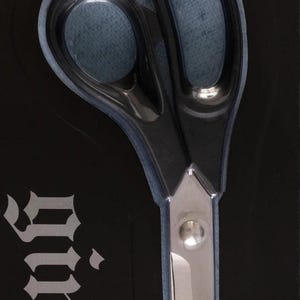 May include: Black and silver Gingher lightweight trimmers, 8 inches long, in a black package. The scissors have black handles and silver blades. The packaging includes the brand name and product information.
