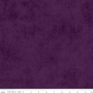 May include: A close-up of a piece of fabric in a deep purple hue. The fabric has a textured, velvety appearance, with subtle variations in color and a soft sheen. The image includes a ruler with inch measurements.