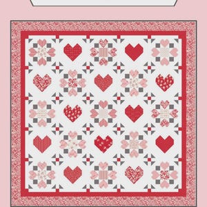 Könnte beinhalten: Ein roter, rosa und weißer Quilt mit Herz- und Blumenmustern. Der Quilt zeigt den Text "Sew-N-Quilt" und "Surrounded By Love". Der Quilt hat einen roten Rand und einen rosa Hintergrund.