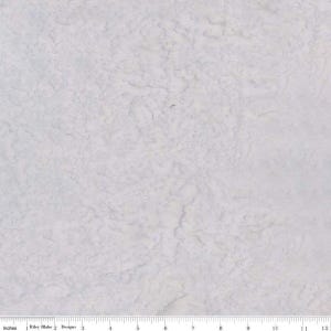 May include: A light grey fabric with a textured, mottled pattern. The fabric has a subtle, organic design, with variations in tone creating a sense of depth. The image includes a ruler along the bottom edge, with the text "Riley Blake Designs".