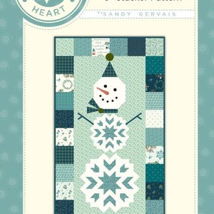Puede incluir: Un patrón de acolchado titulado #787 Frosty 5" Stacker Pattern de Sandy Gervais. El diseño presenta un muñeco de nieve central hecho de dos grandes formas de copo de nieve blanco, una cabeza con nariz de zanahoria y un sombrero a cuadros, bordeado por cuadrados azules.