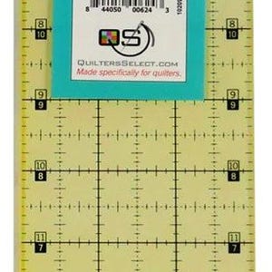 May include: A clear plastic quilting ruler, 7.6 cm by 45.7 cm, with black markings and a turquoise label. The ruler has a non-slip coating and is designed for accurate fabric measuring and cutting. The text "SELECT" and "3" x 18" Ruler" are visible.