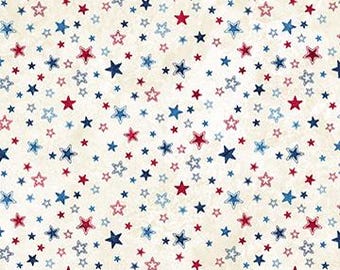 May include: A fabric print featuring a cream-colored background with a scattered pattern of small stars in shades of red, navy blue, and light blue. A ruler at the bottom shows measurements in inches, indicating a scale of 12 inches across.