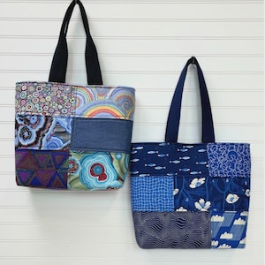 May include: Two patchwork tote bags with black handles. The bags feature various blue and patterned fabrics. The text "That Patchwork Tote" is above the bags. The bags are approximately 12 inches high, 11 inches wide, and 3.5 inches deep.