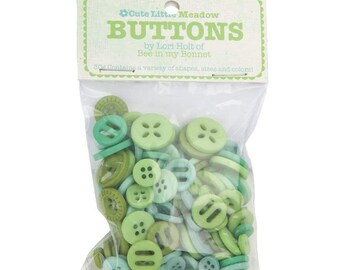 Może przedstawiać: Przezroczysta plastikowa torba wypełniona zielonymi guzikami w różnych odcieniach. Etykieta głosi "Cute Little Meadow BUTTONS" autorstwa Lori Holt of Bee in my Bonnet. Guziki mają różne kształty i rozmiary.