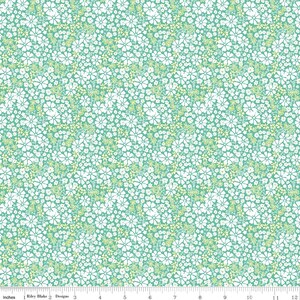 May include: A teal fabric featuring a dense, repeating pattern of small white flowers and light green leaves. A ruler at the bottom edge shows a scale of 12 inches, with the text Riley Blake Designs printed along the measurement markings.