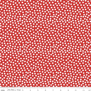 Può includere: Un tessuto rosso caratterizzato da un fitto motivo di piccoli pois bianchi irregolari. Un righello bianco è visibile lungo il bordo inferiore, mostrando una scala di 30 cm. Il testo Riley Blake Designs è stampato sul righello in basso a sinistra.