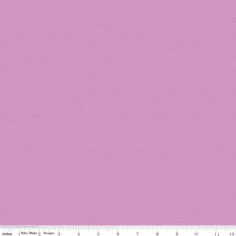 May include: A close-up of a fabric with a small, repeating dot pattern in a light purple color. The fabric is measured in inches along the bottom edge.
