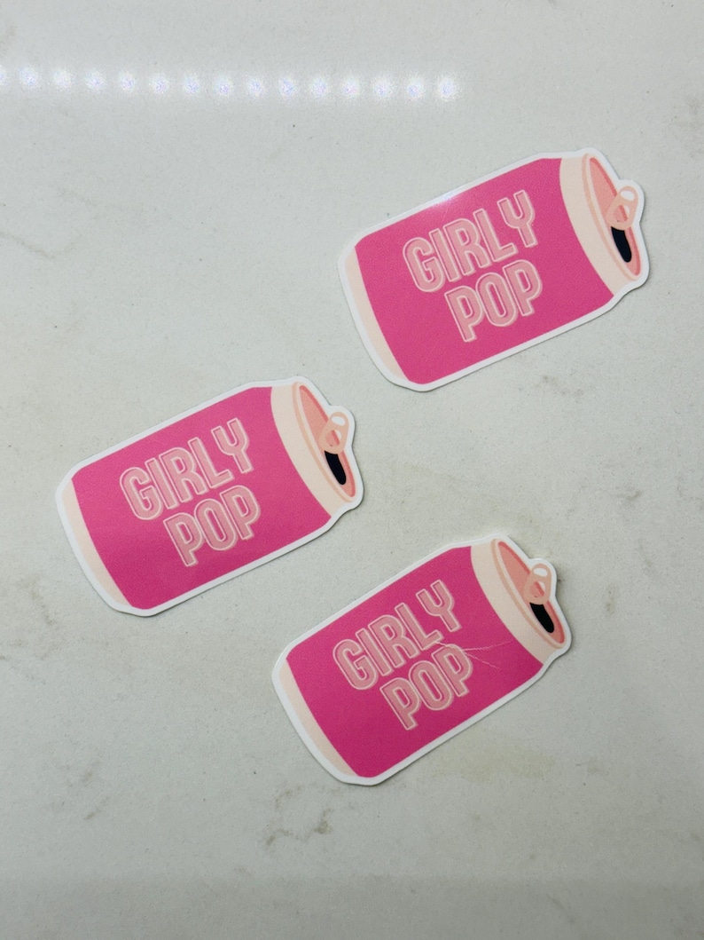 May include: Three pink and white stickers shaped like soda cans with the text "Girly Pop" on each.