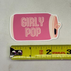 May include: Pink and white sticker of a can with the text "Girly Pop" on it. The sticker is about 2 inches wide.