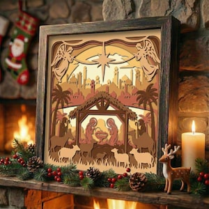 Peut inclure: Une œuvre d'art en bois en couches encadrée représentant une scène de Noël. L'image montre la nativité avec des anges, une étoile et un paysage urbain dans des tons bruns et beiges. L'œuvre est exposée sur une cheminée avec des décorations de Noël.