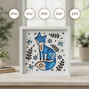 Peut inclure: Une œuvre d'art en papier en couches encadrée représentant un renard bleu avec des motifs floraux et de feuilles. Le renard est placé sur un fond blanc avec des découpes florales et de feuilles supplémentaires. Le cadre est blanc. Types de fichiers : PNG, SVG, PDF, DXF, EPS.