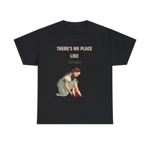 May include: Black t-shirt featuring a graphic of Dorothy from The Wizard of Oz. The text "THERE'S NO PLACE LIKE 127.0.0.1" is printed on the shirt.