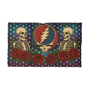May include: A rectangular blanket featuring a central skull design with a red and blue color scheme and a lightning bolt. Two skeleton figures flank the central design, with red roses at the bottom. The background is a blue and purple pattern.