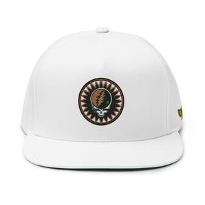 May include: White flat-peak cap with an embroidered emblem featuring a skull, lightning bolt, and sunburst design in brown, green, and gold. A small green and gold emblem is on the side.