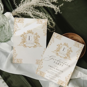 May include: Two white graduation party invitations with gold floral designs and the letter "E". One invitation reads "Graduation Party" and includes event details. The invitations are on a white cloth.
