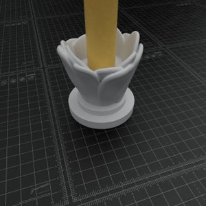 May include: White ceramic candle holder shaped like a flower with a round base. The candle holder is empty and has a yellow candle inside.