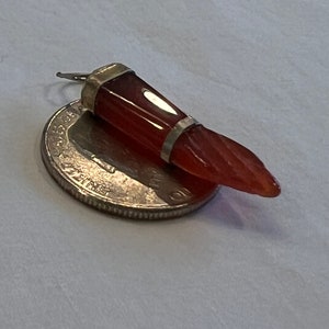May include: A red carnelian gemstone pendant with silver accents. The pendant is shaped like a tooth and is about 1 inch long.