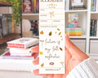 May include: A beige bookmark with the text "BOOKREVIEW" at the top, followed by sections for title, author, and notes. The bookmark features fall-themed illustrations, including a pumpkin and falling leaves, with the phrase "fiction is my fall aesthetic."
