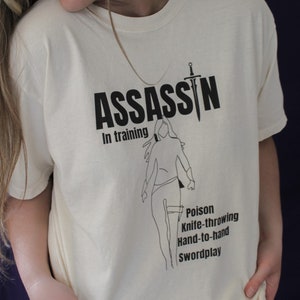 Moordenaar in training Bookish Merch Swordplay Hand-to-Hand meswerpend gif BookTok T-shirt