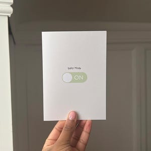 Tarjeta de felicitación con el mensaje "Baby Mode", baby shower, revelación de género, bienvenida al bebé