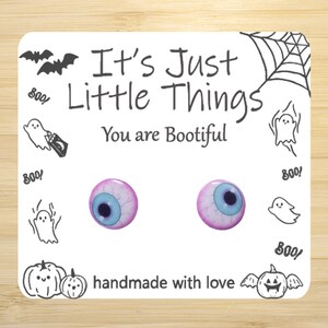 May include: A pair of pink and blue eye earrings with a white background. The earrings are handmade and have the text "It's Just Little Things You are Bootiful" on the card.