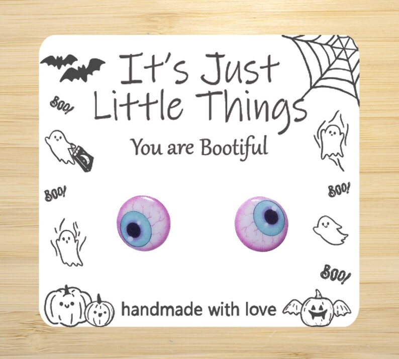May include: A pair of pink and blue eye earrings with a white background. The earrings are handmade and have the text "It's Just Little Things You are Bootiful" on the card.