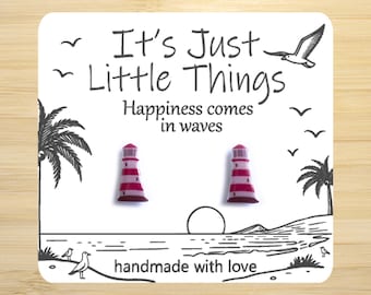 May include: A white card with the text "It's Just Little Things" and "Happiness comes in waves." Two red and white lighthouse earrings are featured. The card also includes illustrations of palm trees, birds, and a sunset. The text "handmade with love" is also included.