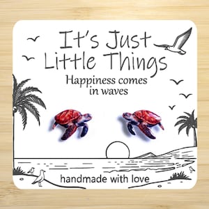 May include: A white card with the text "It's Just Little Things" and "Happiness comes in waves." Two turtle earrings are featured. The card also includes illustrations of palm trees, birds, and a beach scene. The phrase "handmade with love" is also present.