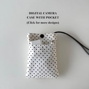 May include: A white digital camera case with black polka dots and a pocket. The case has a black strap and a black button closure. The text "DIGITAL CAMERA CASE WITH POCKET (Click for more designs)" is printed above the case.