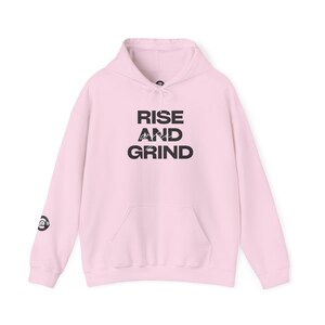 May include: A pink hoodie with a black graphic that says "RISE AND GRIND" on the front.