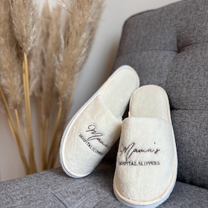 May include: A pair of white, fluffy hospital slippers with the text "Mama's Hospital Slippers" embroidered on each slipper.