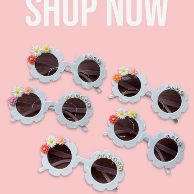 May include: Five pairs of white flower-shaped sunglasses with different names on each pair: Rose,  D'neya, Alma, Drew, and Peyton. Each pair has a small flower decoration on the top.